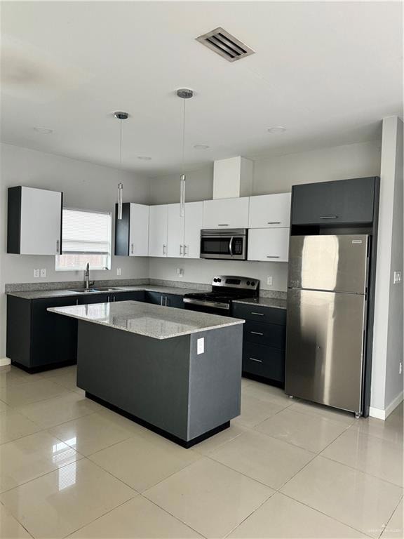 Kitchen featuring stainless steel range with electric cooktop, white cabinetry, a kitchen island, refrigerator, and decorative light fixtures