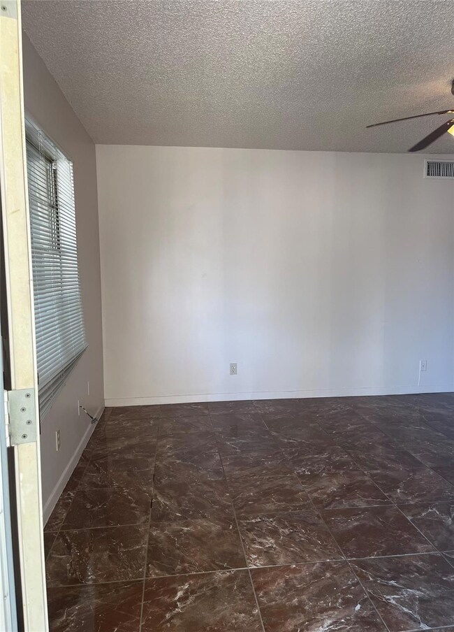 Spare room with ceiling fan, a textured ceiling, 