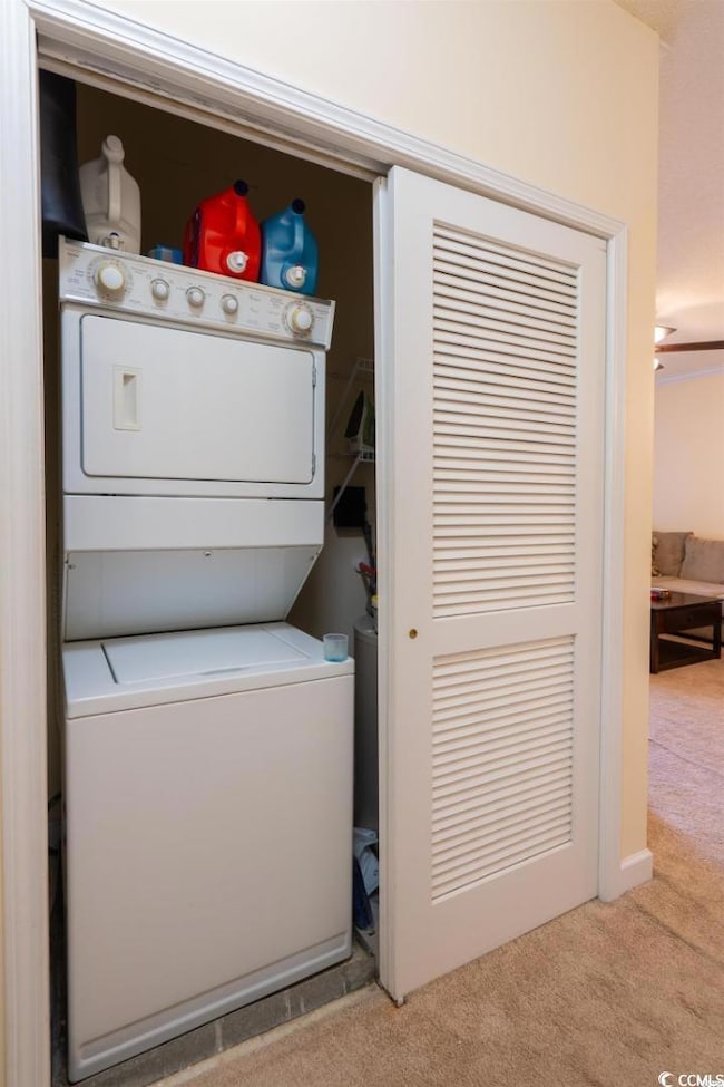 Laundry area featuring stacked washer and clothes dryer and light colored carpet