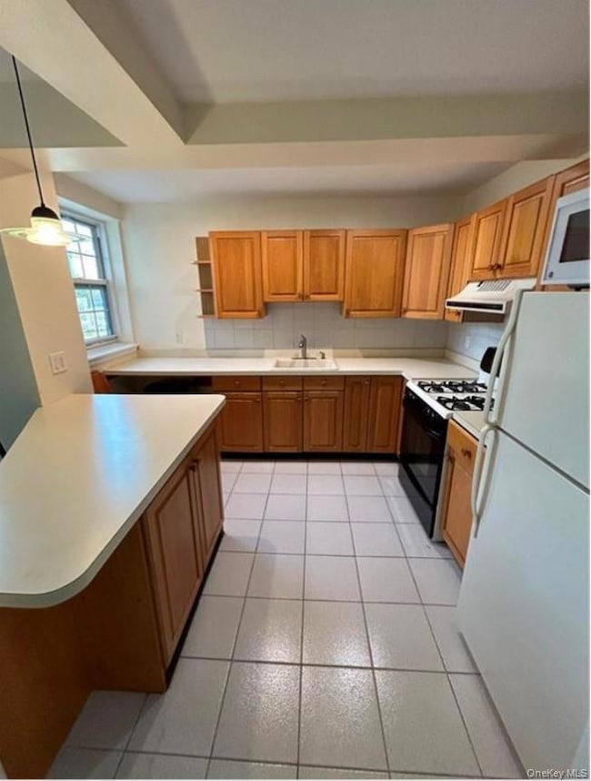 Kitchen with decorative light fixtures, white appliances, sink, and light tile patterned floors