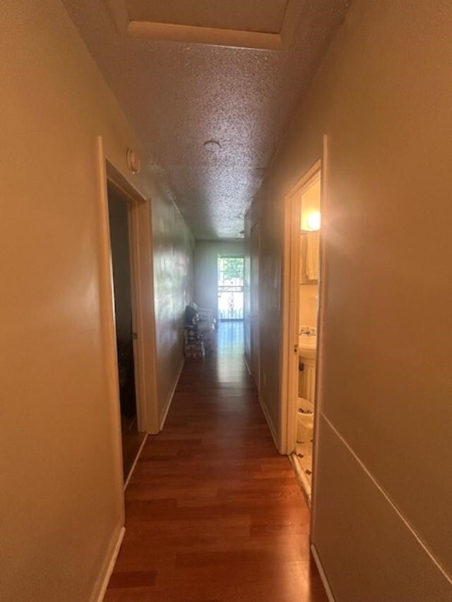 Hall with a textured ceiling and wood finished floors