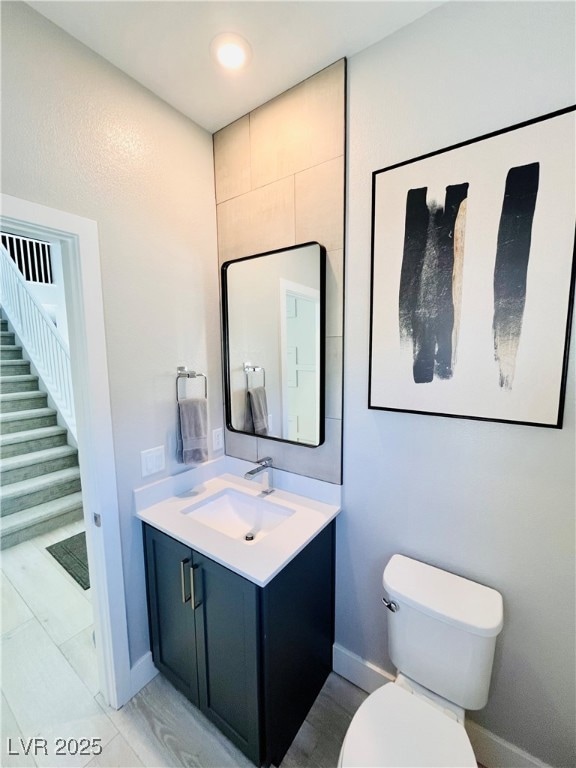 Bathroom featuring baseboards, toilet, and vanity