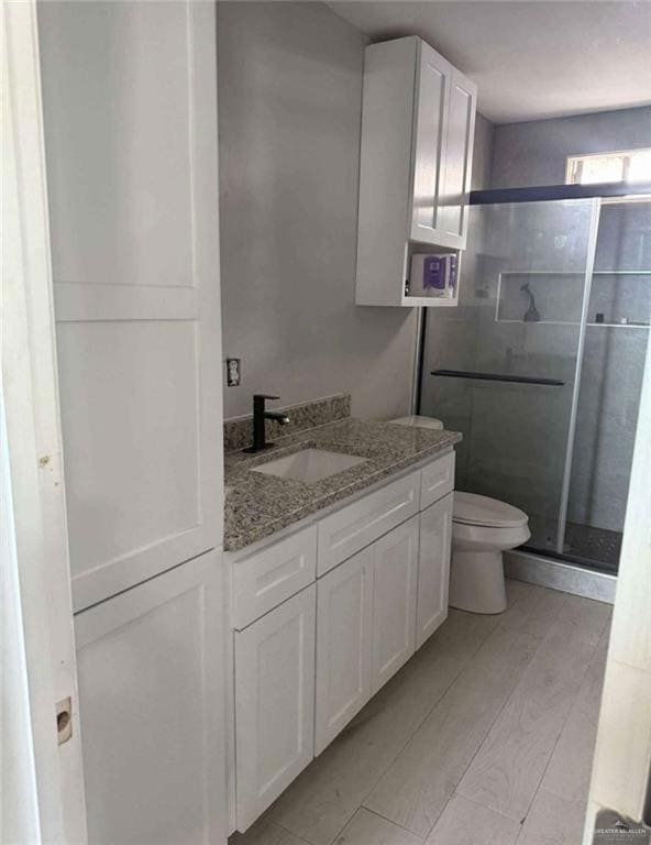 Bathroom with a stall shower, toilet, and vanity