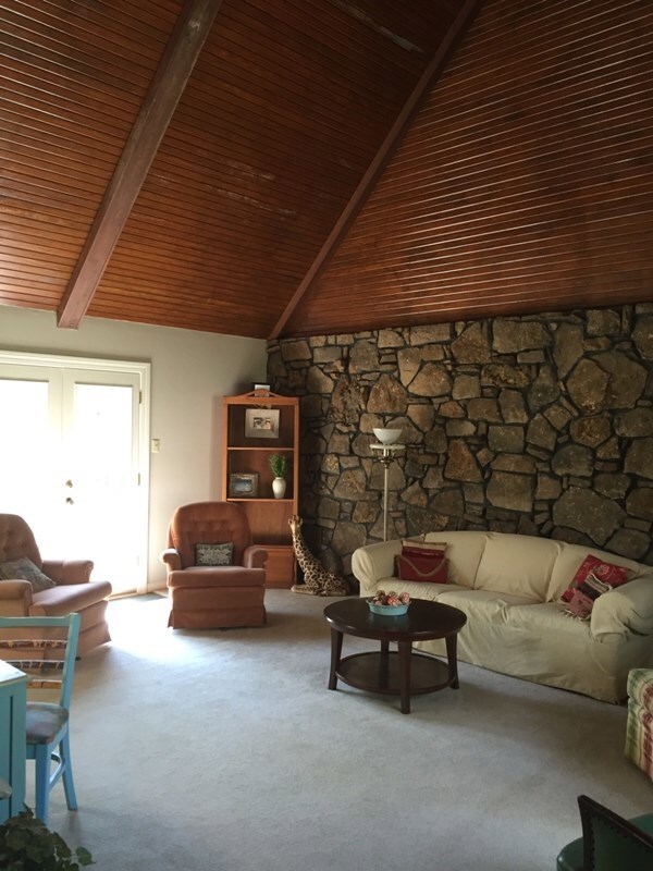 Inviting living room has stone wall, wood-beamed v