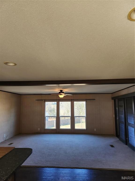 Unfurnished living room with a textured ceiling and ceiling fan