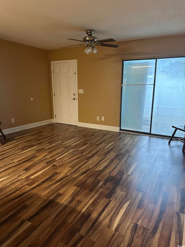 Unfurnished living room featuring dark wood-style floors and a ceiling fan