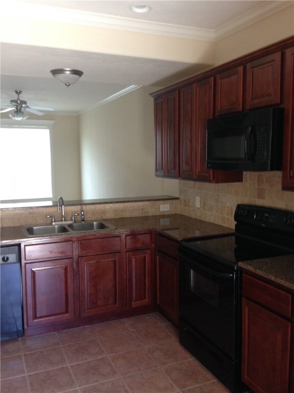 Kitchen with black appliances, sink, ceiling fan, light tile patterned floors, and ornamental molding