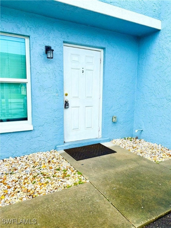 Entrance to property featuring stucco siding