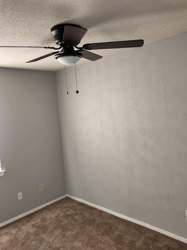 Empty room featuring baseboards, ceiling fan, carp