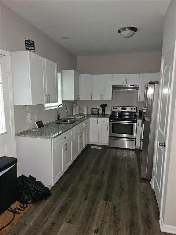 Kitchen featuring appliances with stainless steel finishes, light stone countertops, white cabinetry, dark wood-style flooring, and under cabinet range hood