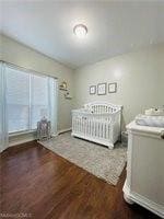 Bedroom with wood finished floors and a crib