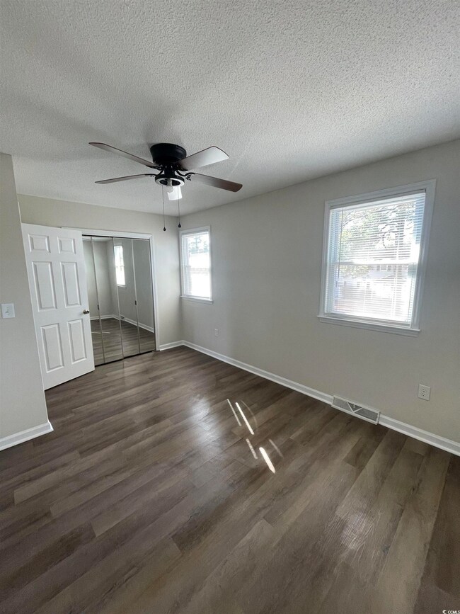 Unfurnished bedroom featuring dark wood finished floors, a textured ceiling, a closet, and a ceiling fan