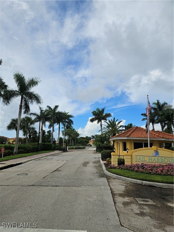 View of asphalt street featuring curbs and a gated entry