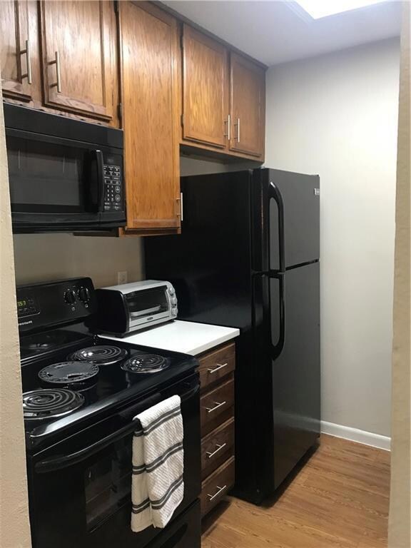 Kitchen featuring black appliances, light wood-ty