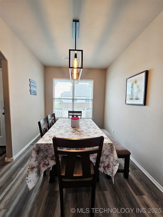 Dining space featuring baseboards and dark wood-style flooring