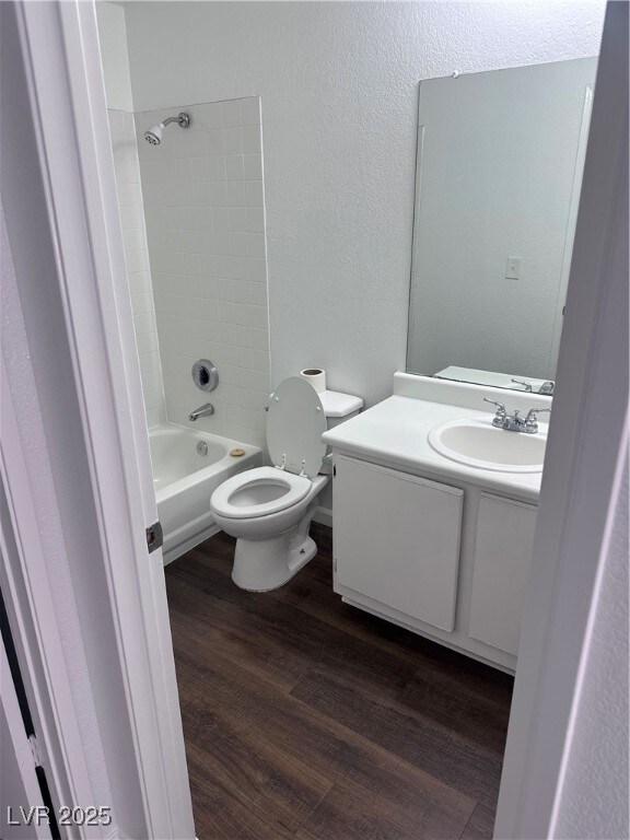 Full bath featuring a textured wall, toilet, wood