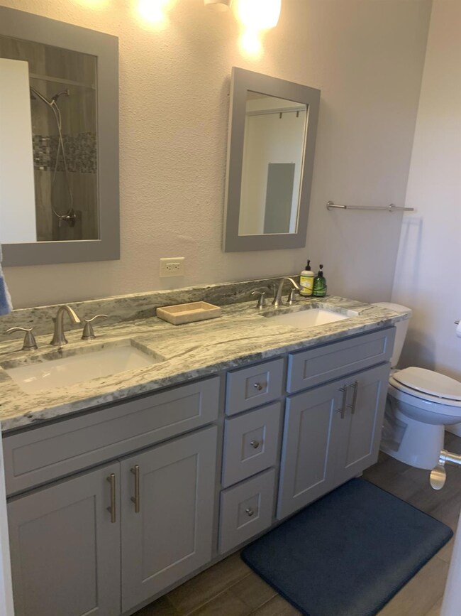 Full bath with double vanity, a shower, and wood 