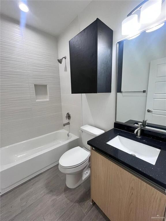 Full bathroom featuring tub / shower combination, wood finished floors, toilet, and vanity