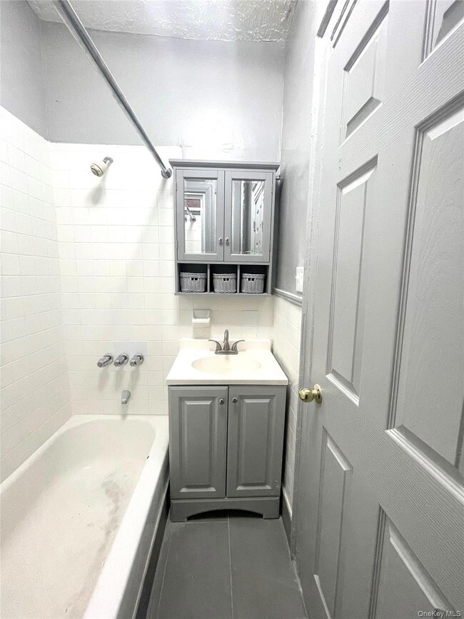 Bathroom with vanity, bathtub / shower combination, a textured ceiling, and dark tile patterned floors