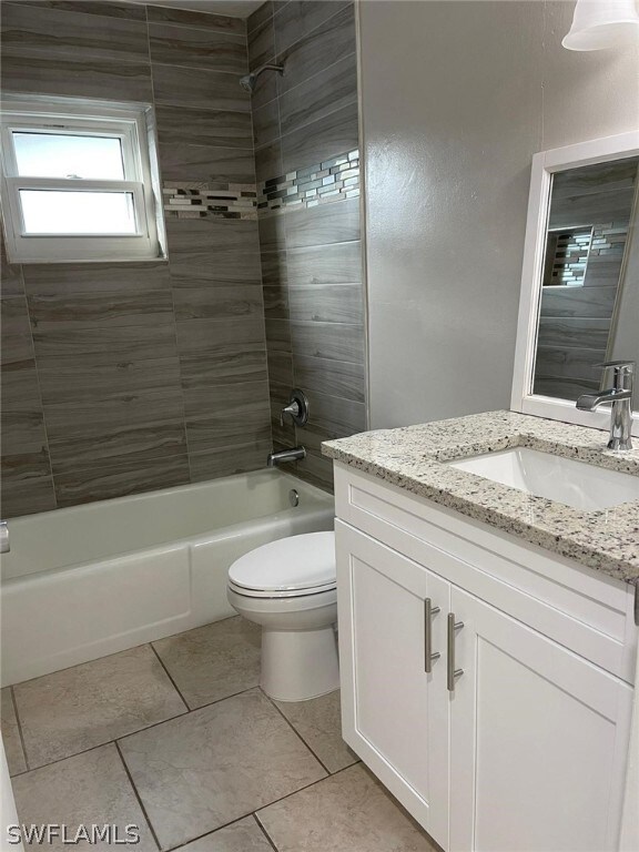 Full bathroom featuring tile floors, tiled shower / bath, toilet, and large vanity