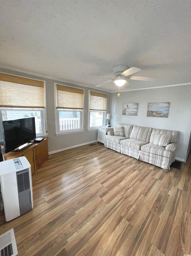 Unfurnished living room with a textured ceiling, wood finished floors, and ceiling fan