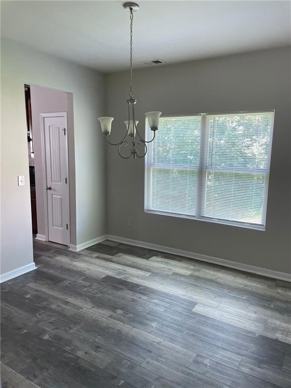 Unfurnished dining area with a chandelier and wood finished floors