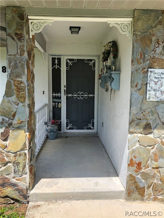 Front entry with decorative rock and screen door.