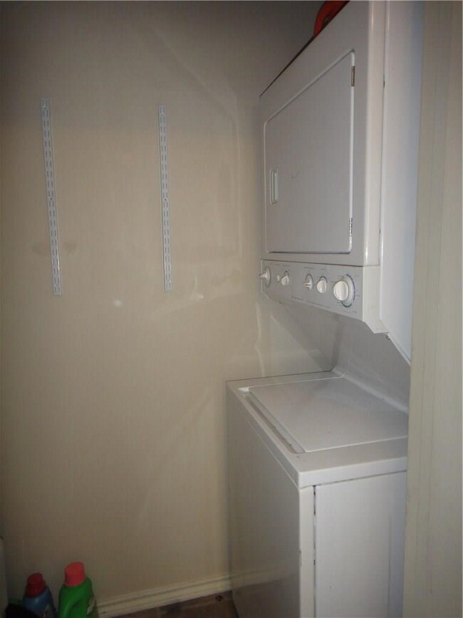 Laundry room with stacked washer and clothes dryer and baseboards