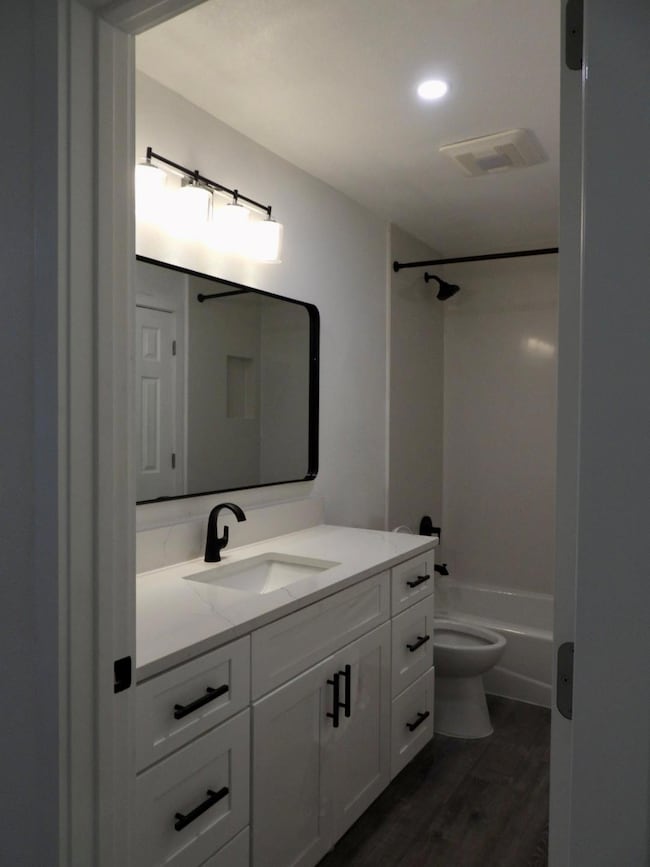 Bathroom with vanity, dark wood-style flooring, tub / shower combination, and recessed lighting