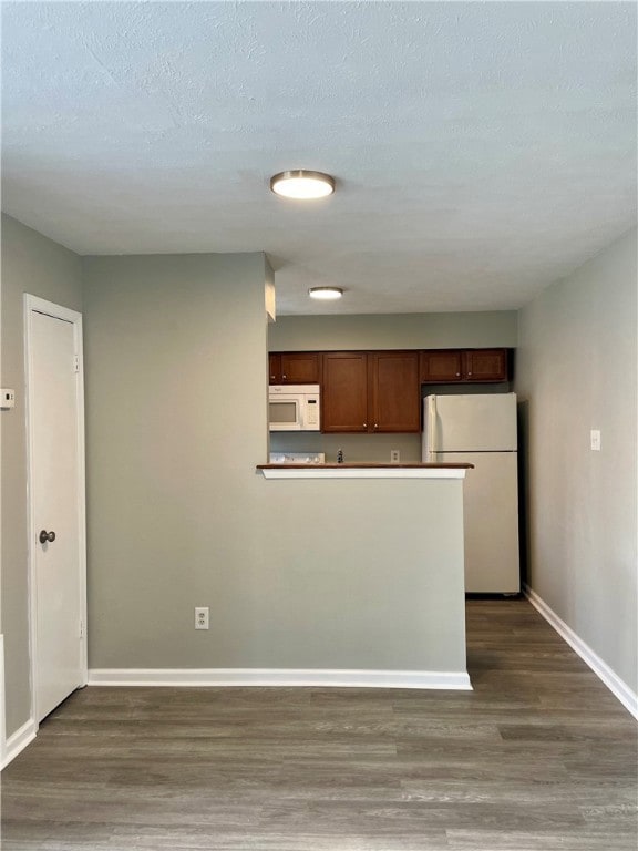 Kitchen featuring white appliances, dark hardwood