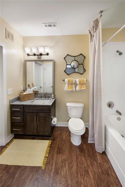 Full bathroom with wood-type flooring, toilet, vanity, and shower / tub combo with curtain