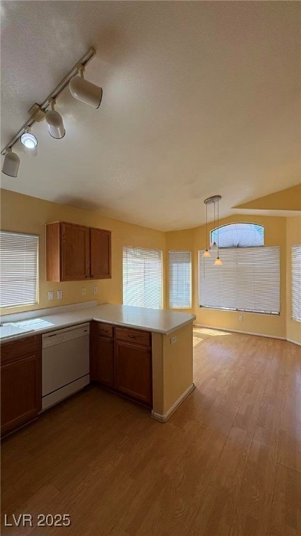 Kitchen featuring brown cabinets, light countertops, dark wood-style floors, white dishwasher, and plenty of natural light