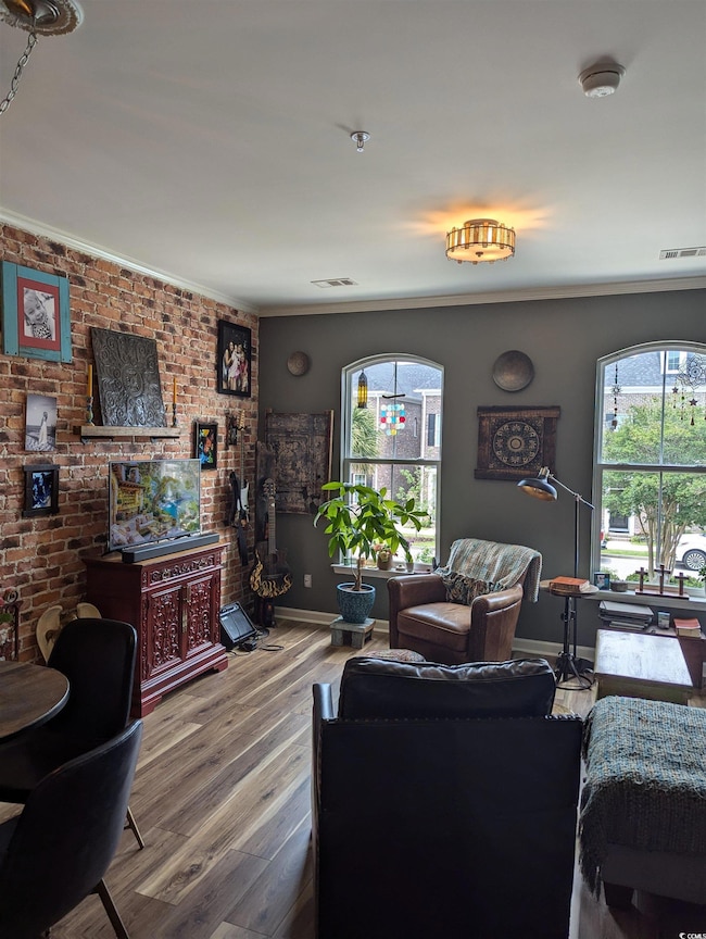 Living area featuring wood finished floors, baseboards, and ornamental molding