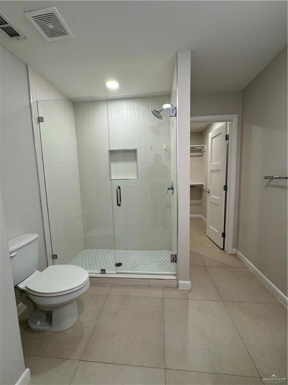 Full bath featuring toilet, tile patterned flooring, visible vents, and a stall shower