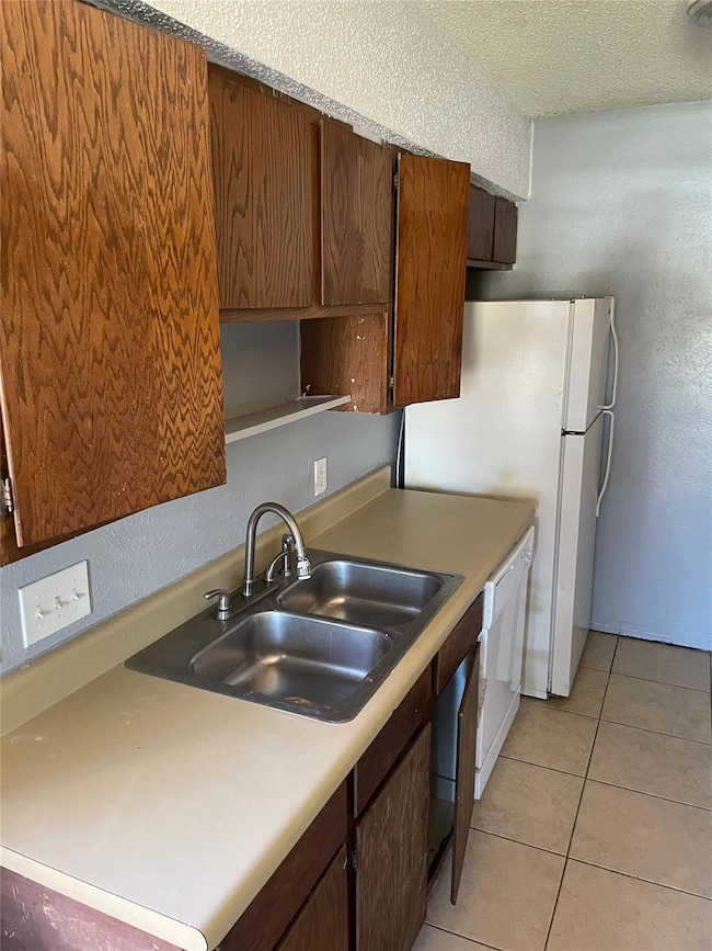 Kitchen with a sink, a textured ceiling, white ap