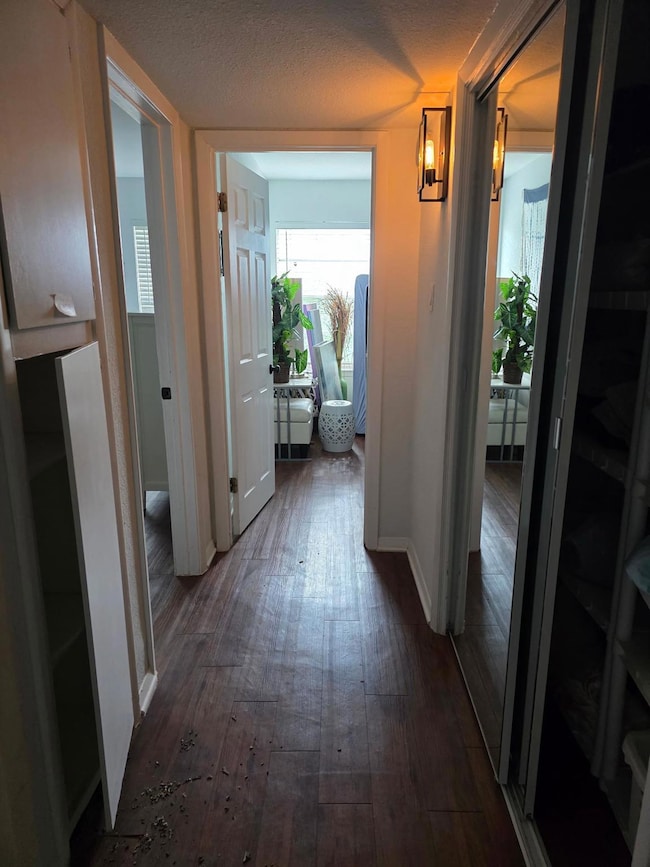 Hallway featuring dark wood-style flooring and ba
