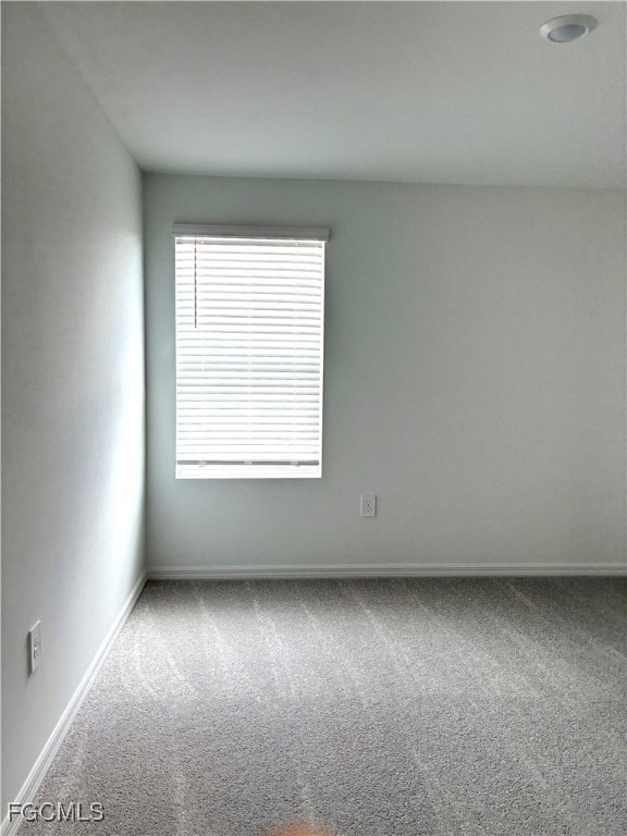 Carpeted spare room featuring baseboards
