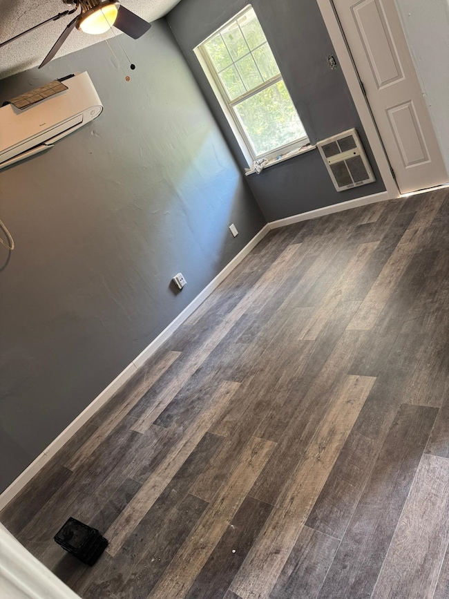 Bonus room with wood finished floors, baseboards, a ceiling fan, and a wall mounted AC