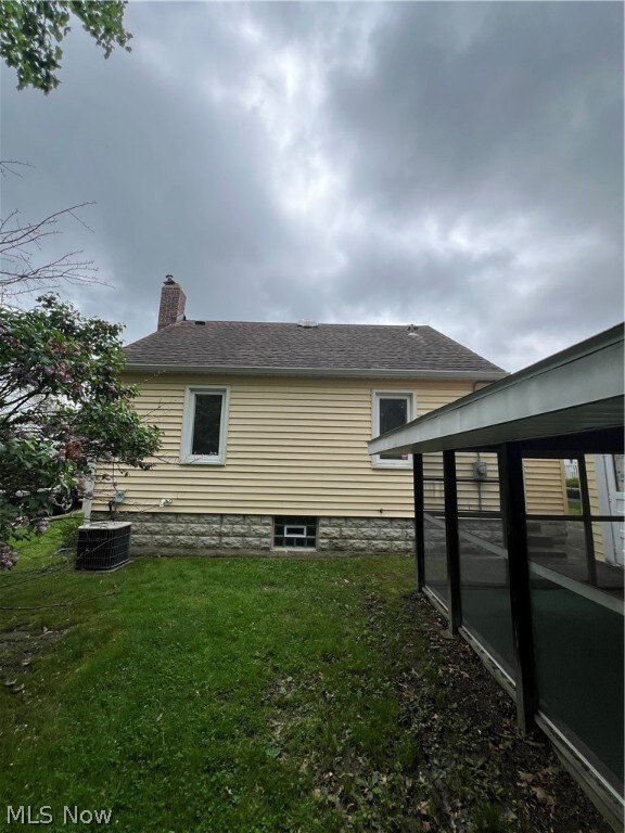 View of home's exterior with a yard and central AC unit