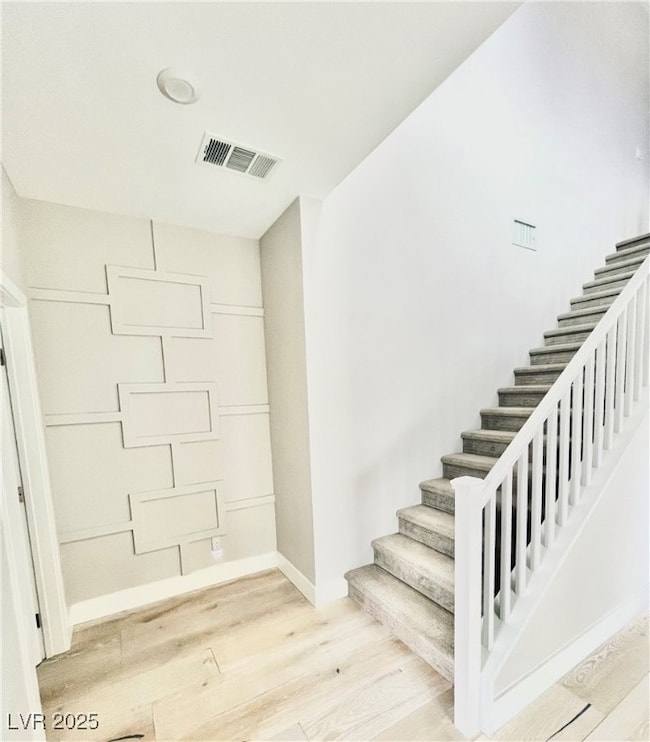 Stairway with wood finished floors and baseboards