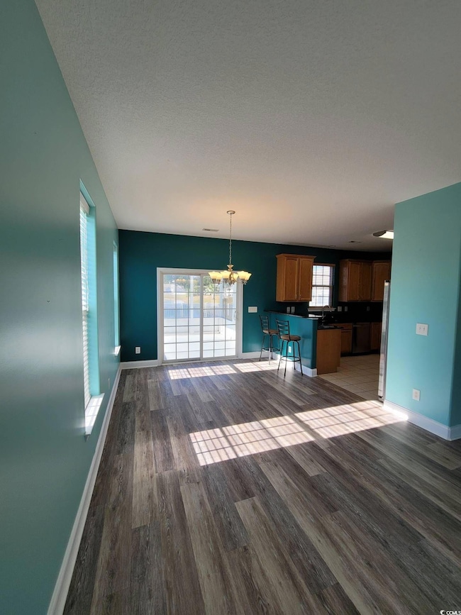 Unfurnished living room featuring a chandelier and wood finished floors