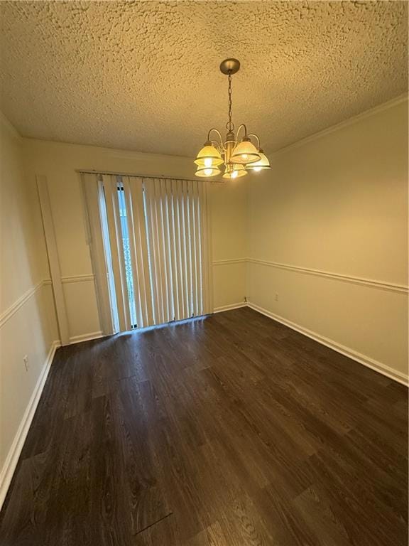 Empty room featuring a chandelier, dark wood finished floors, and a textured ceiling