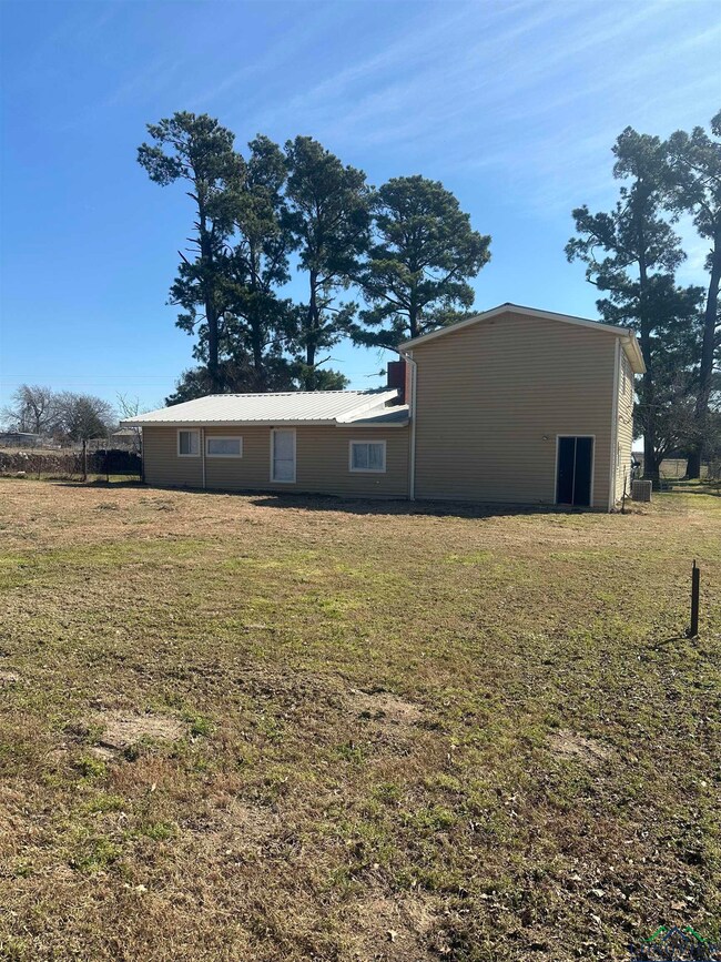 Back of property with metal roof and a yard