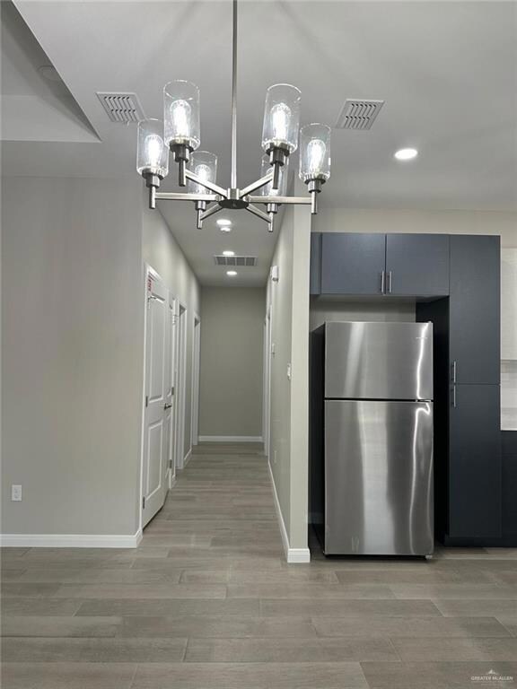 Kitchen featuring light hardwood / wood-style floors, a chandelier, and stainless steel fridge
