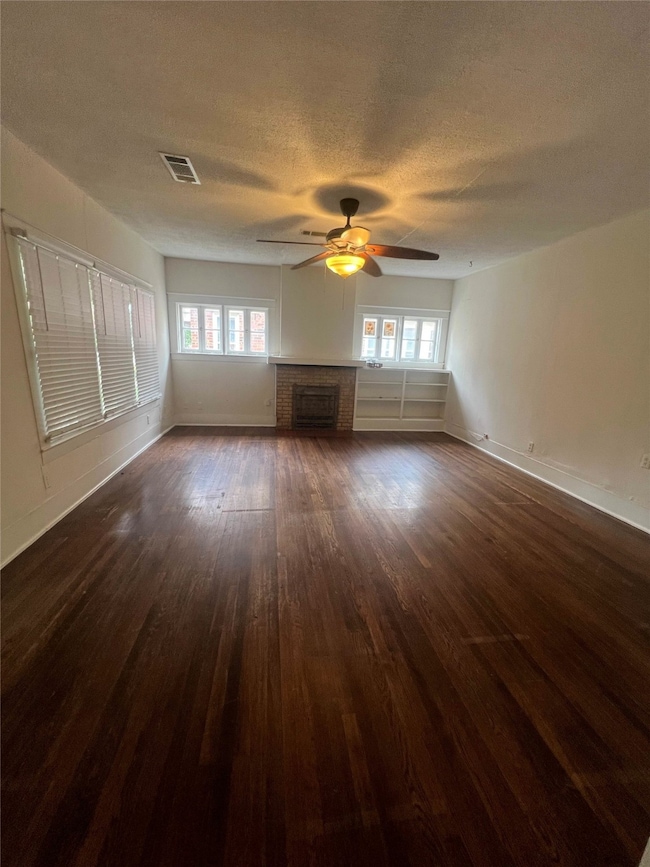 Unfurnished living room with dark wood-style flooring, a fireplace, and a textured ceiling