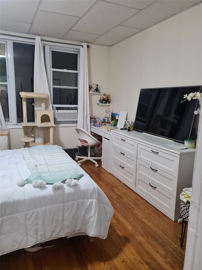Bedroom featuring a drop ceiling, wood finished floors, and a desk