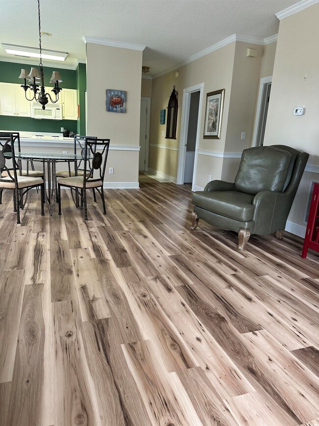 Dining space featuring crown molding, light wood finished floors, a chandelier, and a textured ceiling