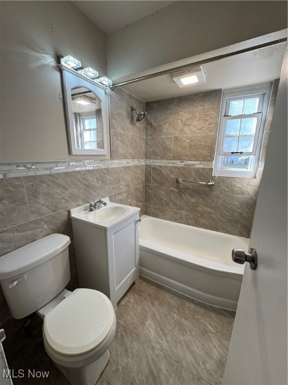 Bathroom featuring tile walls, vanity, plenty of natural light, and bathtub / shower combination