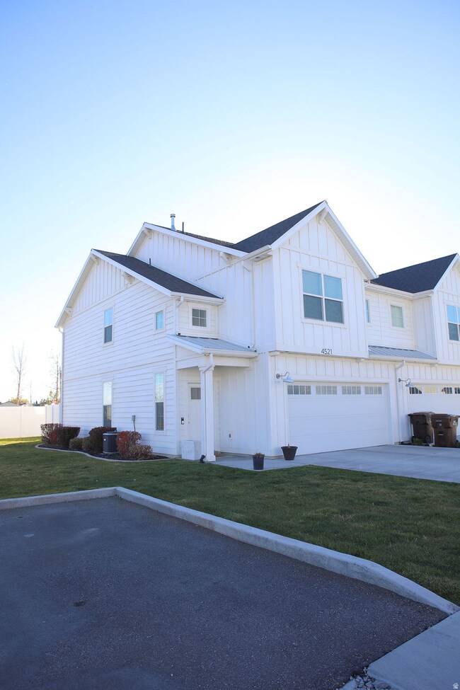 Modern farmhouse style home with board and batten siding, a front yard, a garage, and concrete driveway