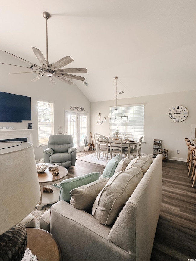 Living area featuring dark wood finished floors, a ceiling fan, and high vaulted ceiling